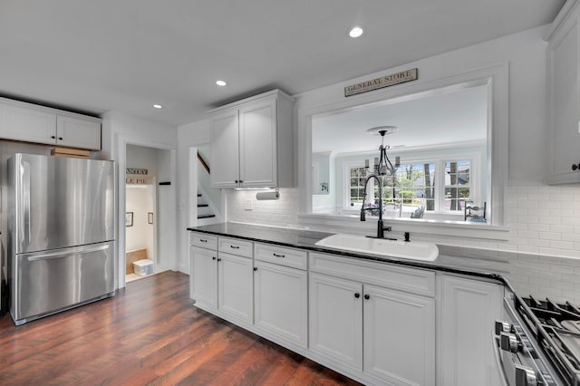 kitchen with white cabinets, decorative backsplash, stainless steel appliances, and a sink