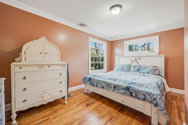bedroom with ornamental molding, baseboards, visible vents, and light wood-style floors