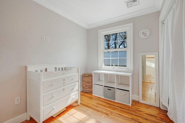 bedroom featuring light wood finished floors, visible vents, baseboards, and ornamental molding