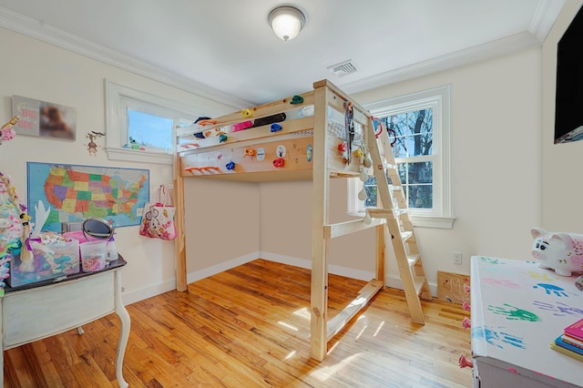 bedroom featuring baseboards, ornamental molding, light wood-style flooring, and visible vents