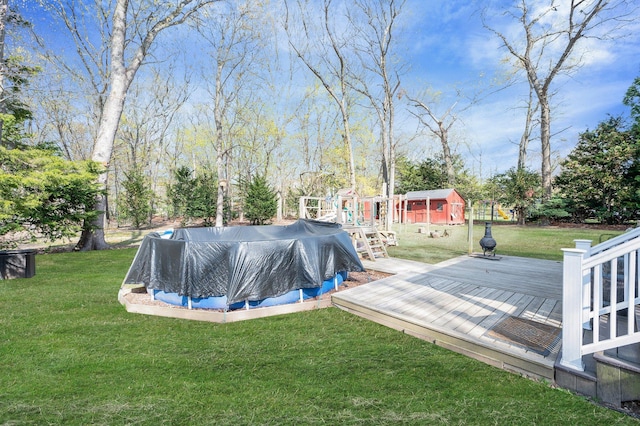 view of pool with a lawn, a deck, a covered pool, and area for grilling