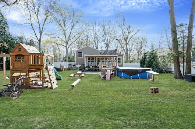 back of house featuring a playground, a chimney, a covered pool, a lawn, and a deck