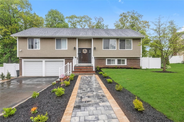 split foyer home featuring asphalt driveway, an attached garage, and a shingled roof