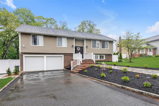 bi-level home featuring driveway, an attached garage, and roof with shingles