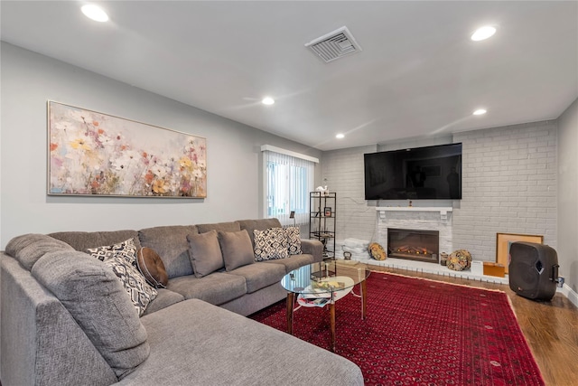 living area featuring wood finished floors, a glass covered fireplace, and recessed lighting