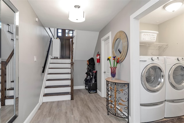 washroom featuring washer and dryer, light wood finished floors, and baseboards