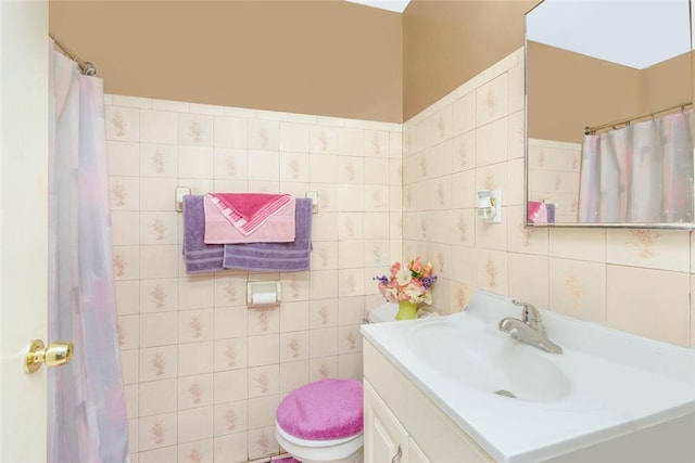 bathroom with tile walls, toilet, and vanity