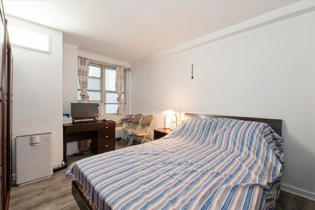 bedroom with radiator heating unit and wood finished floors