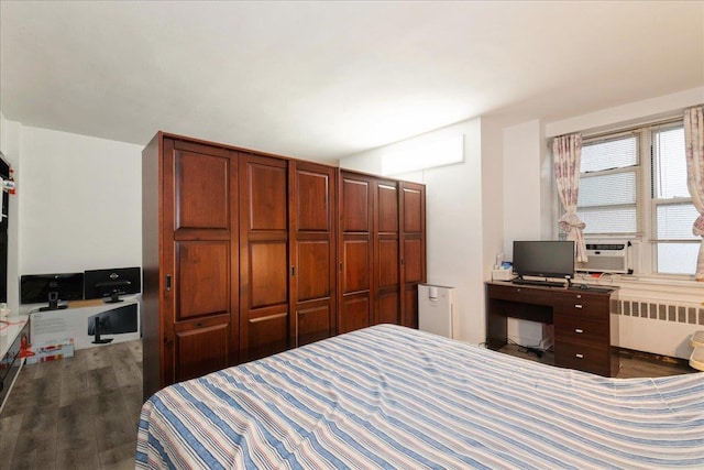 bedroom with cooling unit, wood finished floors, and radiator heating unit
