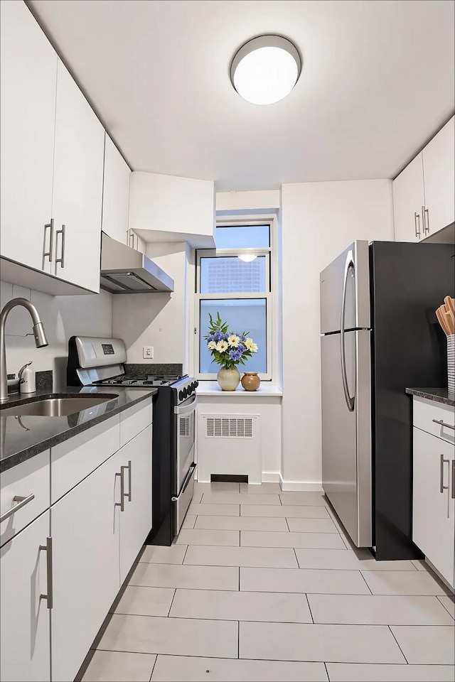 kitchen with under cabinet range hood, baseboards, a sink, dark stone counters, and appliances with stainless steel finishes