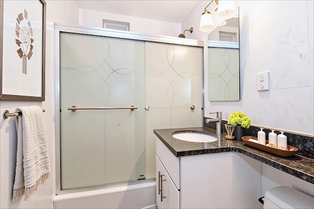bathroom featuring toilet, vanity, and combined bath / shower with glass door