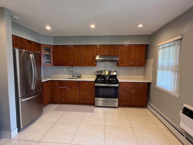 kitchen featuring tasteful backsplash, under cabinet range hood, light countertops, baseboard heating, and appliances with stainless steel finishes