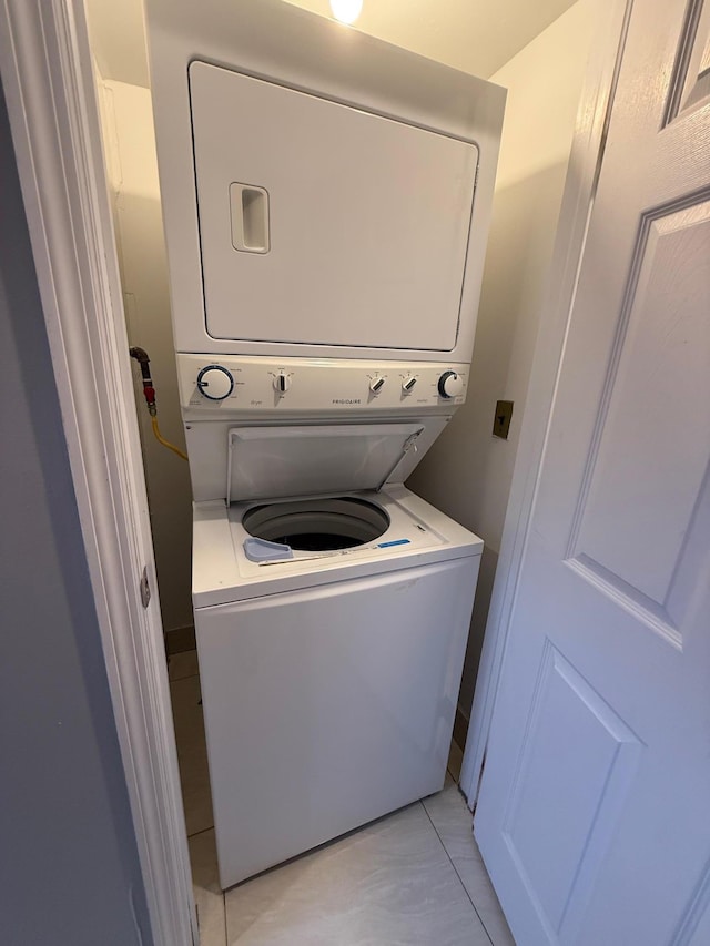 laundry room featuring laundry area, visible vents, light tile patterned flooring, and stacked washer and dryer