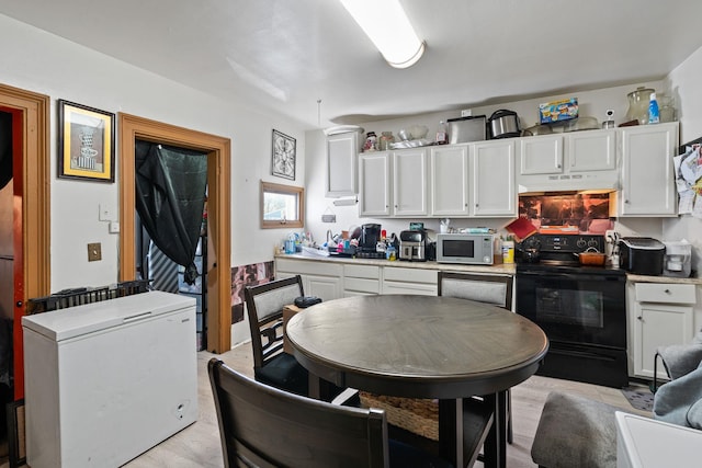 kitchen with under cabinet range hood, white appliances, white cabinetry, and light countertops