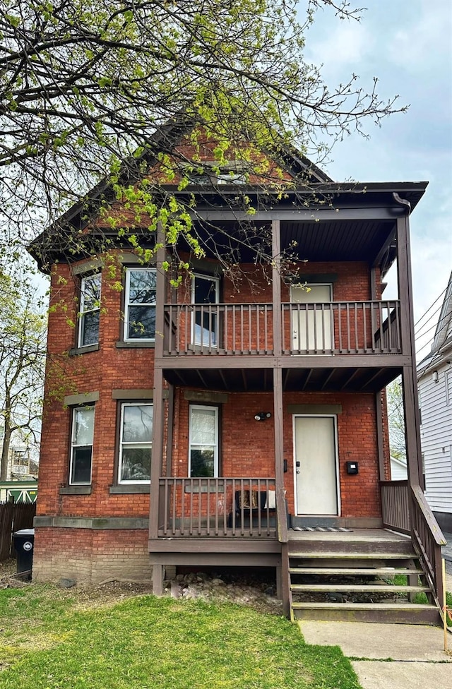 back of house featuring brick siding and a balcony