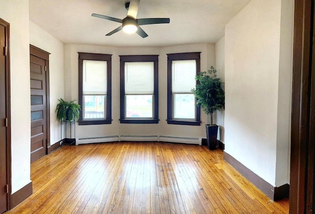 empty room with a baseboard heating unit, light wood-style floors, a ceiling fan, and baseboards