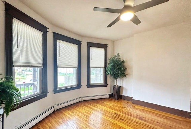 unfurnished room featuring a ceiling fan, a baseboard radiator, light wood finished floors, and baseboards