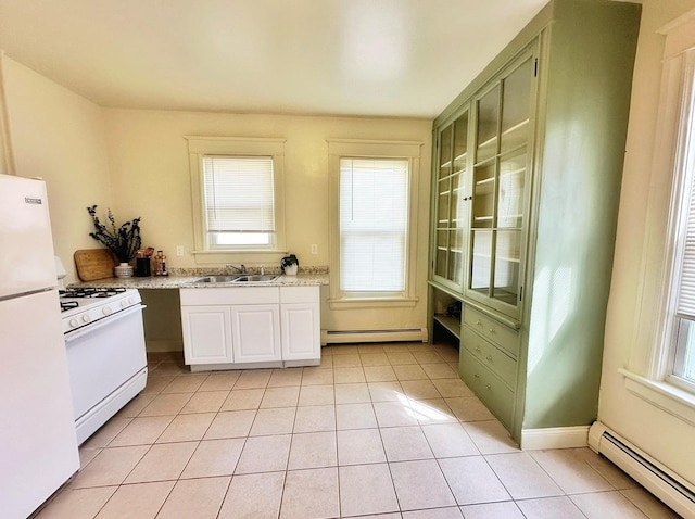 kitchen with a baseboard radiator, light tile patterned flooring, white appliances, and a wealth of natural light