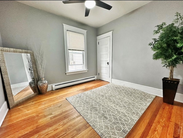bedroom featuring baseboards, baseboard heating, a ceiling fan, and wood finished floors