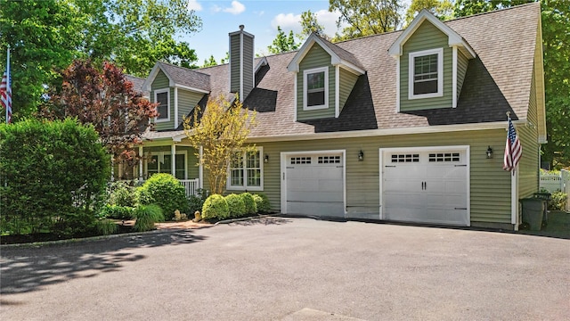 cape cod home with asphalt driveway, a chimney, and roof with shingles