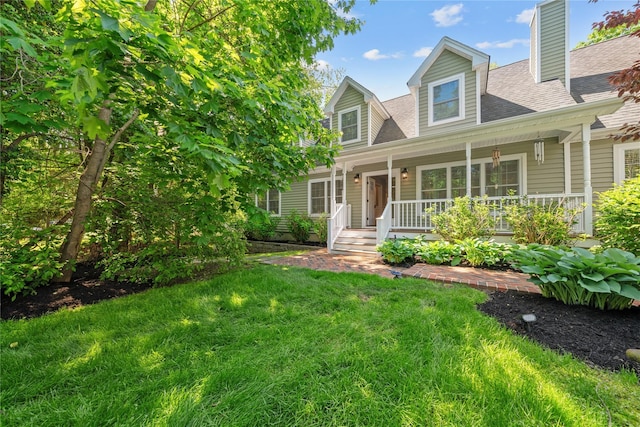 cape cod-style house with roof with shingles, a porch, a front yard, and a chimney