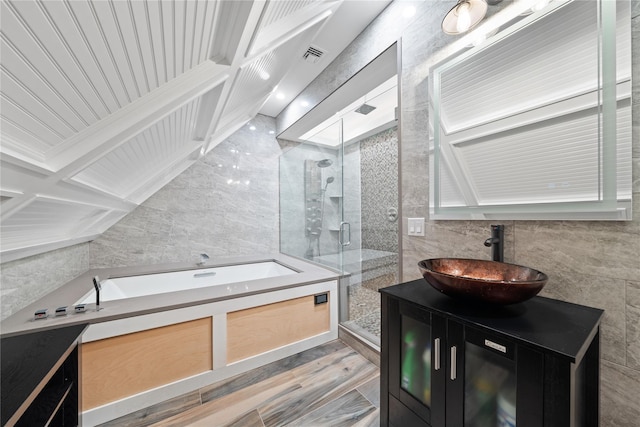 bathroom with tile walls, a stall shower, vanity, a garden tub, and wood finished floors