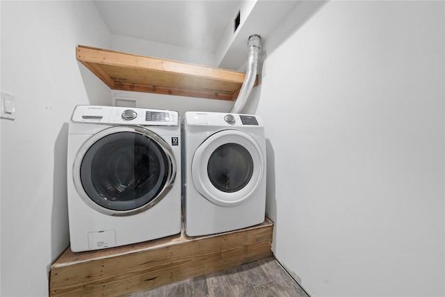 clothes washing area featuring washer and dryer and wood finished floors