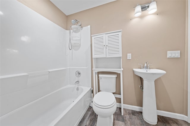 bathroom with wood finished floors, toilet, baseboards, and bathing tub / shower combination