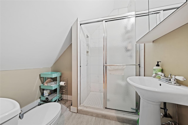 bathroom featuring toilet, a stall shower, baseboards, and vaulted ceiling