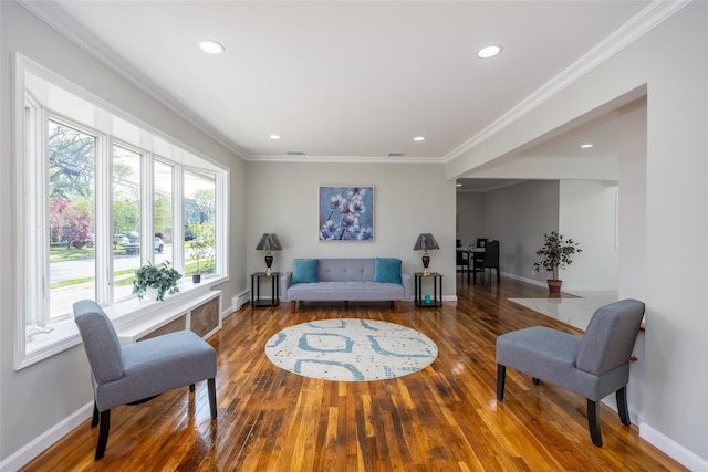 living area with wood finished floors, baseboards, ornamental molding, and recessed lighting