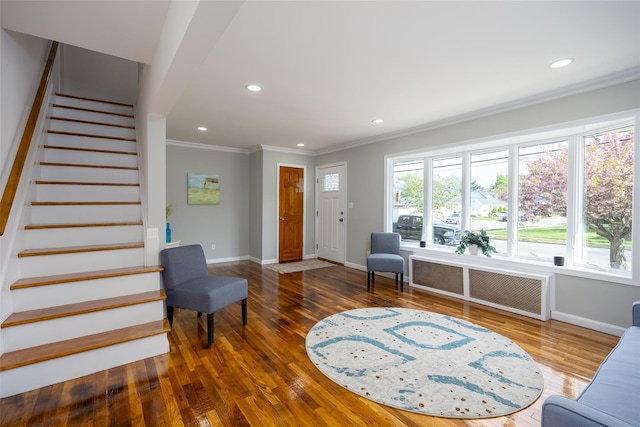 living area with crown molding, baseboards, wood finished floors, stairs, and recessed lighting