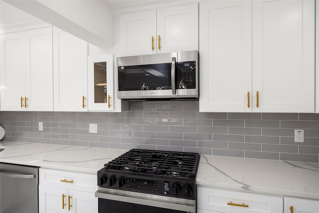 kitchen with stainless steel appliances, white cabinetry, decorative backsplash, and light stone countertops
