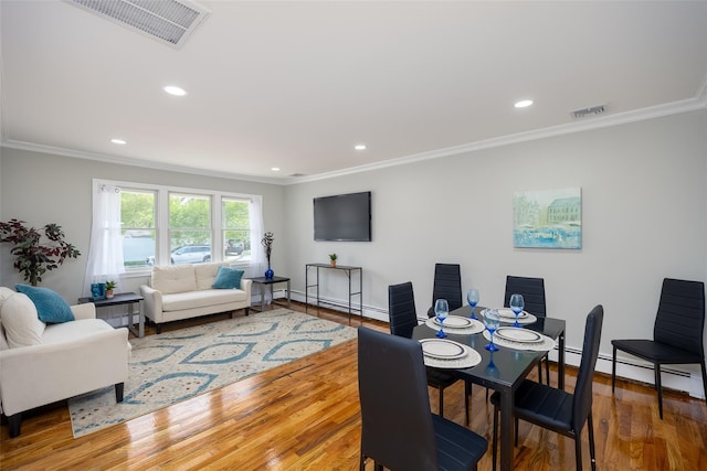 dining space with ornamental molding, a baseboard heating unit, wood finished floors, recessed lighting, and baseboards