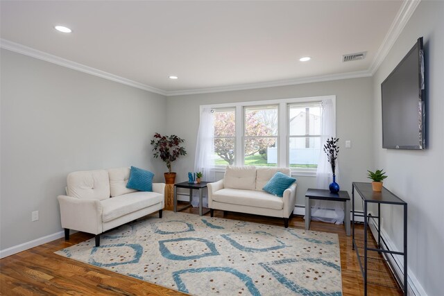 sitting room with wood finished floors, crown molding, baseboards, and recessed lighting