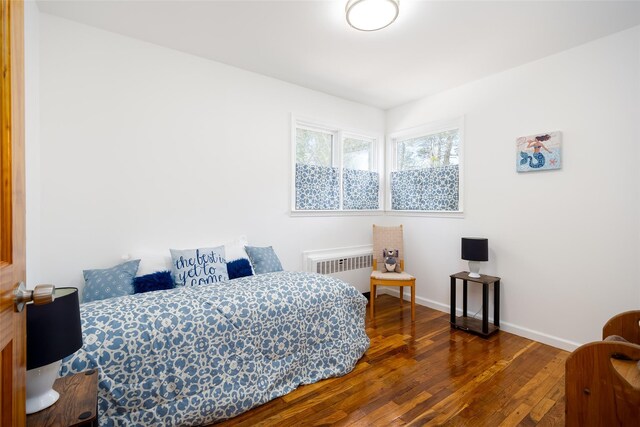 bedroom featuring radiator heating unit, hardwood / wood-style floors, and baseboards