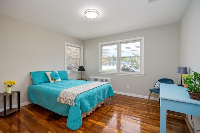 bedroom with baseboards, wood finished floors, and radiator heating unit