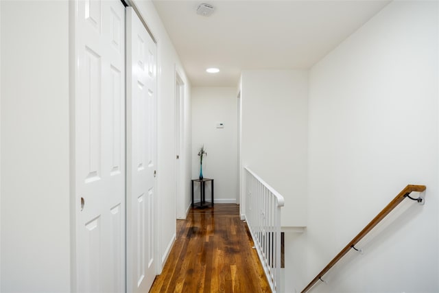 corridor with an upstairs landing, wood finished floors, and baseboards