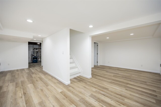 finished basement with stairway, light wood-style floors, baseboards, and recessed lighting