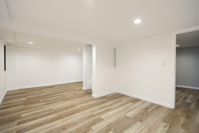finished basement featuring light wood-style flooring, baseboards, recessed lighting, and stairway