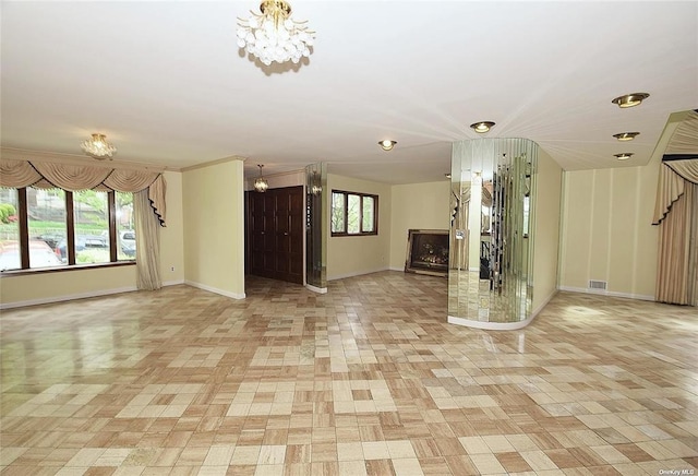 unfurnished living room featuring a chandelier, stairway, baseboards, and visible vents