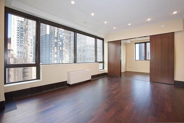 40 Broad St Unit 28H, New York Manhattan, NY 10004 - unfurnished bedroom featuring radiator heating unit, wood finished floors, recessed lighting, and baseboards