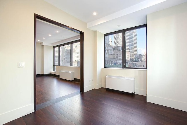 40 Broad St Unit 28H, New York Manhattan, NY 10004 - unfurnished room featuring radiator heating unit, hardwood / wood-style flooring, baseboards, recessed lighting, and a city view
