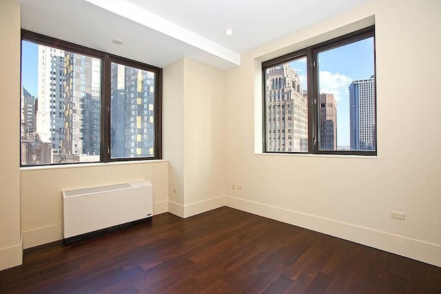 40 Broad St Unit 28H, New York Manhattan, NY 10004 - spare room with radiator, baseboards, hardwood / wood-style flooring, a skyline view, and recessed lighting