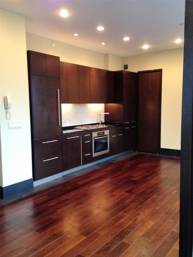 40 Broad St Unit 28H, New York Manhattan, NY 10004 - kitchen with stainless steel oven, modern cabinets, recessed lighting, dark wood-type flooring, and tasteful backsplash