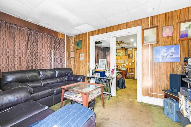 living room with wooden walls, carpet floors, and a ceiling fan