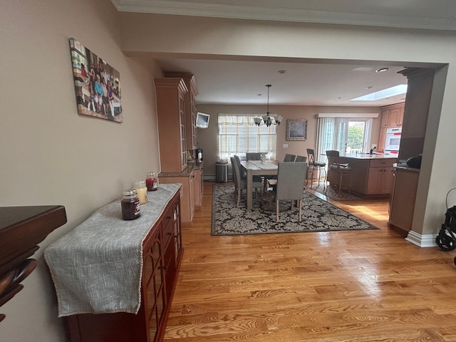 36 Shore Dr W, Copiague, NY 11726 - dining room featuring ornamental molding, baseboard heating, light wood-style flooring, and a chandelier