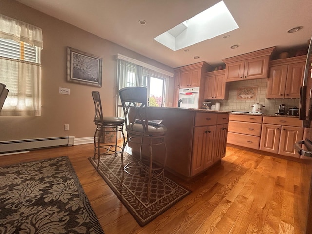 36 Shore Dr W, Copiague, NY 11726 - kitchen with a center island, a skylight, backsplash, white oven, and a baseboard radiator