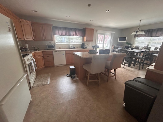36 Shore Dr W, Copiague, NY 11726 - kitchen with light brown cabinetry, white appliances, an inviting chandelier, a kitchen island, and light countertops