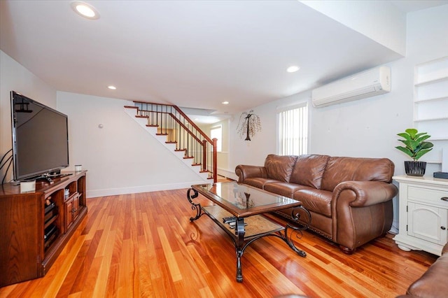 living room with light wood finished floors, stairs, a wall unit AC, and recessed lighting