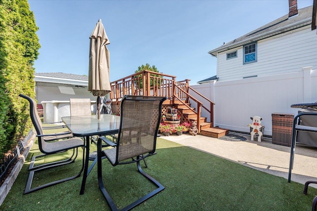 view of patio with outdoor dining area, stairway, and fence